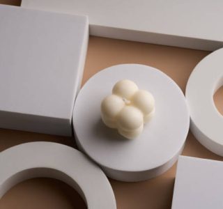 white bubble candle on white podium on beige background, minimal copy space background for presentation cosmetic product with bright natural sunlight